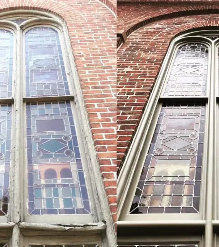 Restored leaded glass panel being reinstalled in a white-painted hallway of a historic brownstone